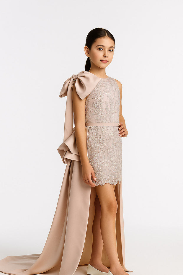 Young girl wearing a beige lace dress with a long bow on a white background